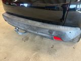 the rear end of a black car with a red tail light