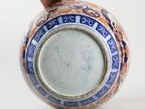 a hand holding a vase with a blue and orange design