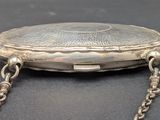 a silver purse with a chain around it on a table