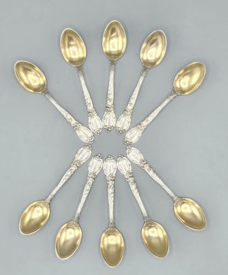 six cuillères en argent disposées en cercle sur une surface grise