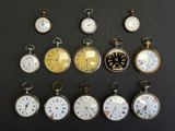 many different types of pocket watches displayed on a table
