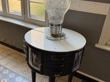 une table sur laquelle est posée une lampe, devant une fenêtre
