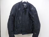 black motorcycle jacket hanging on a hanger on a white wall