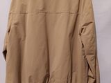 a tan jacket hanging on a hanger against a white wall