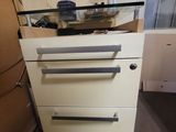 a white cabinet with three drawers and a glass top