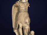une vieille statue représentant un homme avec un chien, sur fond bleu