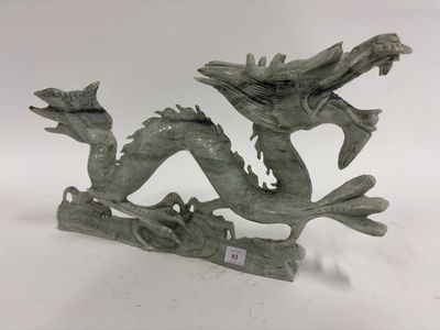 statue d'un dragon perché sur une branche, avec une étiquette autour du cou