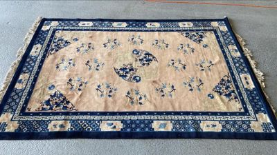 une photo d'un tapis oriental bleu et beige posé au sol