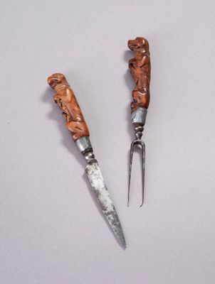 two knives with carvings on them sitting next to each other on a white surface