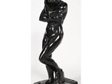 une statue noire représentant un homme les bras croisés