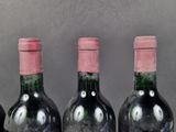 three bottles of red wine are lined up on a table