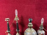 trois lampes anciennes posées sur une table en bois, avec un mur rouge en arrière-plan