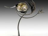 sculpture en métal argenté représentant une fleur posée sur un socle et dotée d'une horloge