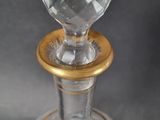 a clear glass bottle with a gold rim on a table