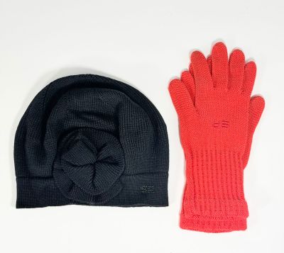 une paire de gants tricotés rouges et noirs et un bonnet posés sur une surface blanche