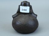 une image représentant un petit vase noir sur lequel est accrochée une étiquette