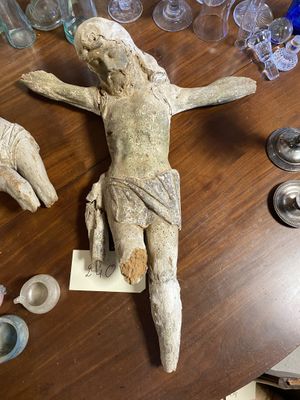 une statue de Jésus posée sur une table en bois, entourée d'autres objets