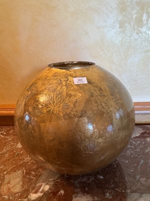 un grand vase posé sur un sol en marbre, près d'un mur