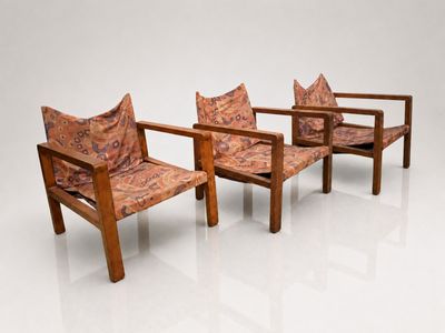 two wooden chairs with patterned cushions sit side by side on a white surface