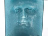 une sculpture en verre représentant le visage d'un homme sur fond blanc