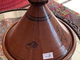 un vase marron posé sur une table en verre, avec un canapé rouge en arrière-plan