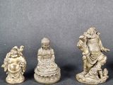 three small statues of buddhas are sitting on a black surface