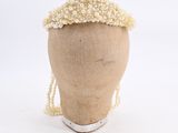 a mannequin head with pearls on it on a white surface