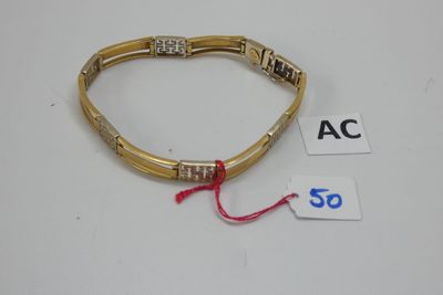 gros plan d'un bracelet en or sur une surface blanche