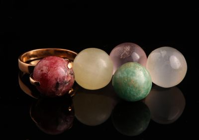 un gros plan sur trois bagues ornées de pierres de différentes couleurs, posées sur une surface noire