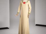 une photo d'un mannequin portant une robe beige ornée de fleurs rouges