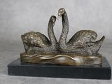 sculpture en bronze représentant deux cygnes sur un lac, avec de l'eau au premier plan
