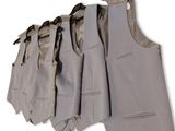 five suits hanging on a clothes rack on a white wall