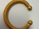 une image d'un bracelet en or sur une surface blanche