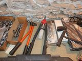 many tools that are sitting on the floor next to a stone wall