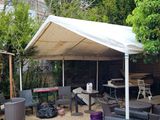 tables and chairs under a canopy in a backyard setting