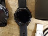 two smart watches sitting on a table next to a laptop