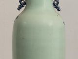 a green vase sitting on a table with a white wall in the background