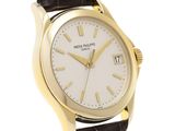 a gold plated wrist watch with a white dial and black leather strap