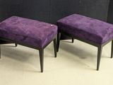 pair of purple upholstered stools in front of a black wall