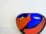 a blue and orange vase with a black base on a white surface