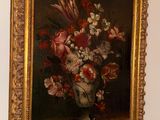 a painting of flowers in a vase hanging on a wall