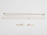 trois colliers en or et une paire de boucles d'oreilles sur fond blanc