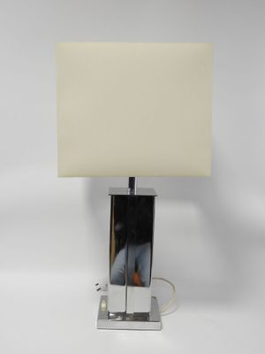 une lampe de table chromée surmontée d'un abat-jour blanc