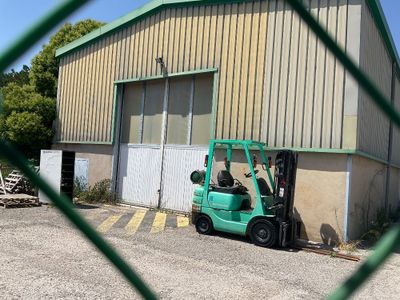 un chariot élévateur garé devant un bâtiment, derrière une clôture grillagée