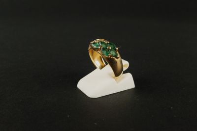 Gros plan sur une bague en or ornée d'une pierre verte