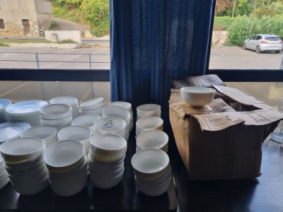 many plates and cups sitting on a table in front of a window