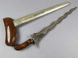 pair of silver and wood daggers on a white surface