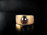 a close up of a gold ring with a red stone in it