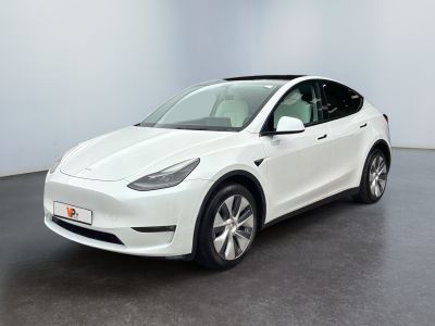 un SUV Tesla blanc garé dans une pièce au sol noir