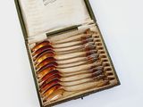 a box with six spoons in it on a white surface